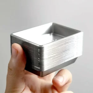 silver-plastic-mini-trays-stack Stack of 25 silver-tone plastic miniature trays held in hand for scale