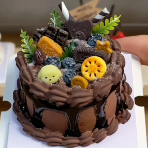 Finished example of a DIY miniature chocolate cake craft kit with fruit-style decorations, leafy accents, and layered dessert details