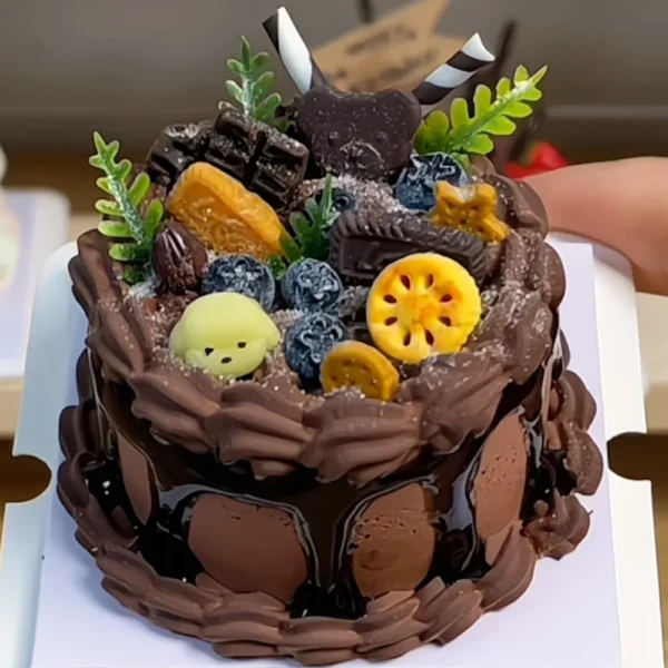 Finished example of a DIY miniature chocolate cake craft kit with fruit-style decorations, leafy accents, and layered dessert details