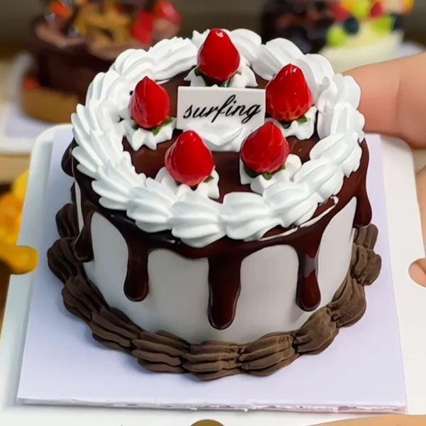 Finished example of a DIY strawberry chocolate cake craft kit with white cream-like piping, chocolate-drip styling, and red berry decorations