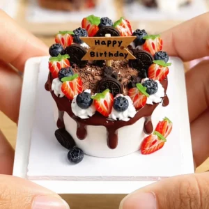 Finished example of a DIY miniature birthday cake kit with chocolate drip, berry decorations, cookie accents, and Happy Birthday topper