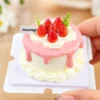 DIY Miniature Strawberry Cake Kit Finished Example Finished example of a DIY miniature strawberry cake kit with pink drip topping, cream-like details, red strawberries, and green accents