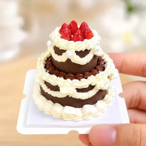 Finished example of a DIY miniature strawberry chocolate cake kit with two tiers, cream-like piping, red strawberries, and pearl accents